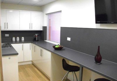 Modern communal kitchen with white cabinetry, dark countertops, and a breakfast bar.