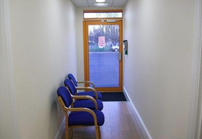Reception waiting area with blue chairs and a glass door leading outside.