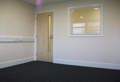 Private office suite with neutral walls, dark carpet, and an internal window.