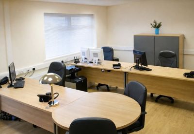 Spacious three-person office suite with light wood desks and black ergonomic chairs.