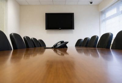 Professional meeting room featuring a large polished wood table and black leather chairs.