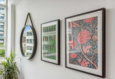 Close-up of framed floral art and a circular mirror hanging on a white wall.