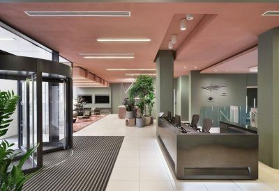 Modern reception lobby with a sleek dark desk and warm pink ceiling.