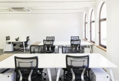 Bright open-plan office with white desks and black mesh chairs.