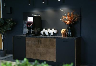 Sleek coffee station with a black machine and modern cabinetry.