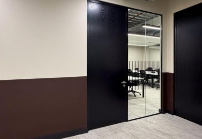 Private office door with silver handle and glass wall revealing an internal desk area.