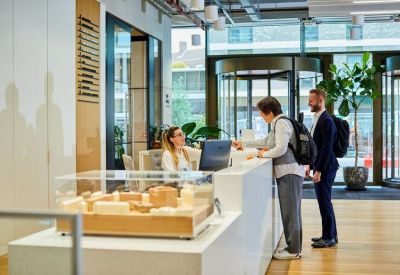 Light-filled reception desk with a white counter and people checking in.