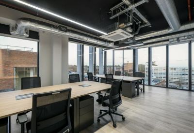 Open-plan workspace with multiple desks and floor-to-ceiling windows.