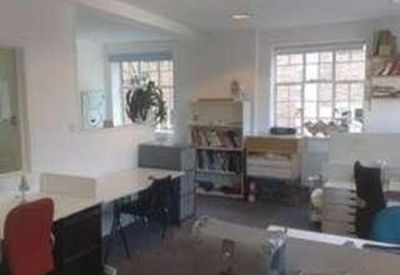 Daylight-filled office interior with multiple desks and professional grey flooring.