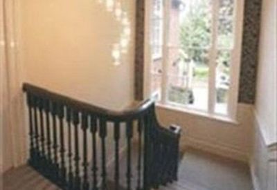 Well-lit landing area featuring a classic dark wood banister and a large window.