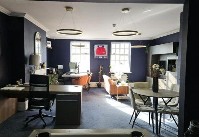 Spacious open-plan workspace with navy blue walls and modern pendant lighting.