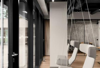 Unique lounge area with contemporary white swing chairs suspended from the ceiling near large windows.