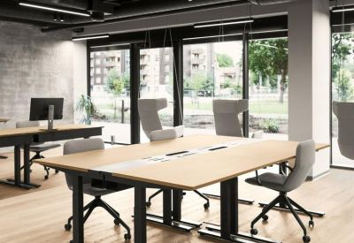 Spacious open-plan office with light wood adjustable desks and black industrial ceilings.