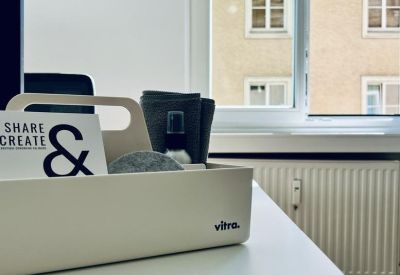 Detail of a white desk organizer holding a Share & Create card next to a window.