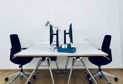 Symmetric dual workstation setup with black ergonomic chairs and white desk.