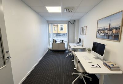 Private office suite with two white desks, ergonomic chairs, and a large window.