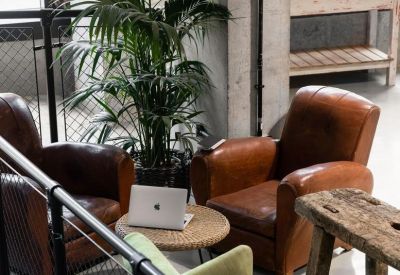 Breakout space with leather club chairs and a wooden bench near a staircase railing.