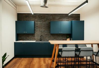 Communal kitchen area featuring teal cabinetry, a brick accent wall, and high-top seating.