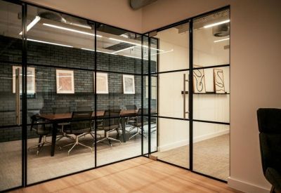 Meeting room with a large wooden table enclosed by industrial glass partitioning.