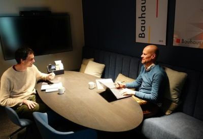 Casual breakout area with blue bench seating and low oval table for collaboration.