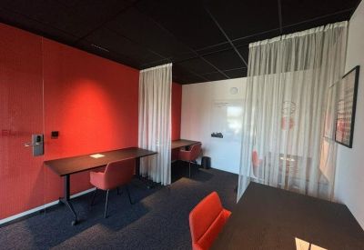 Sleek private workstation area with red feature wall and sheer privacy curtains.
