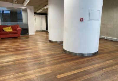 Open plan area with two large white structural columns, hardwood flooring, and a red sofa in the background.