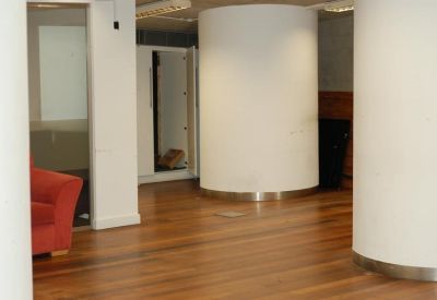 Interior corridor featuring large white cylindrical columns and hardwood floors leading to a red sofa.