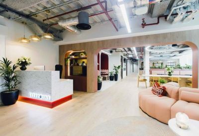 Modern reception lobby with marble desk, wood-paneled archways and vibrant plants.