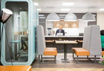 Private phone booth and high-backed booth seating with orange cushions in a breakout area.