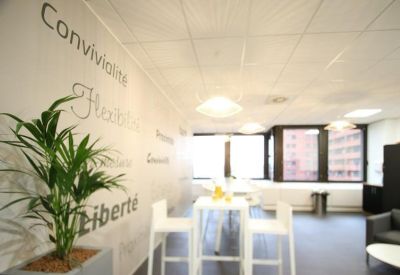 Bright breakout area featuring white high tables and wall graphics with motivational words.