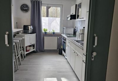 Modern galley kitchen with white cabinetry and a breakfast bar.