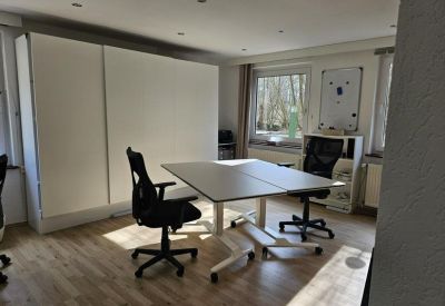 Spacious two-person office with height-adjustable desks and ergonomic chairs.