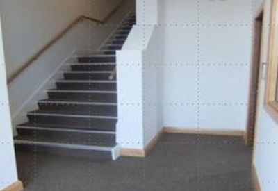 Internal carpeted hallway with a staircase leading to the upper floor and a wall-mounted TV.