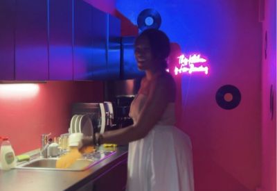 A vibrant red and blue themed kitchen with a checkered floor and neon sign.