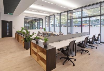 Bright open-plan workspace with wooden floors and floor-to-ceiling windows.