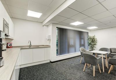 Communal kitchen and dining area with grey seating and wooden countertops.