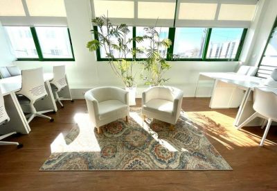 Lounge area with cream tub chairs and a patterned rug in front of large windows.