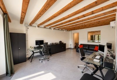 Open office area featuring two large desks with dual monitors and a black leather sofa.