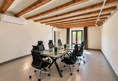 Bright conference room with a glass-top table, ergonomic chairs, and exposed wood ceiling beams.