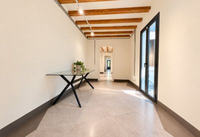Clean corridor featuring a glass table, tall windows, and views into adjacent office suites.