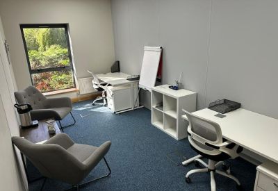 Internal two-person office suite with white desks and grey armchairs.
