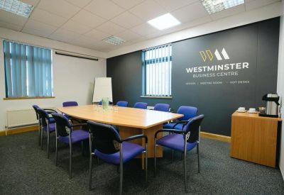 Boardroom with a wooden table, blue chairs, and a branded feature wall.