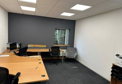 Spacious office with L-shaped wooden desks and a dark accent wall.