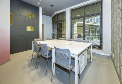 Four-person office space with white desks, grey chairs, and a feature wall with yellow built-in niches.