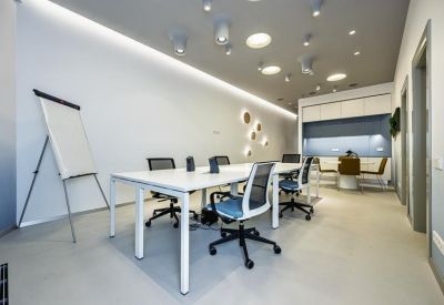 Spacious boardroom with a long white table, ergonomic blue-seated chairs, and recessed ceiling lighting.
