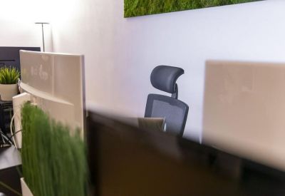 View of an ergonomic black office chair positioned between computer monitors.