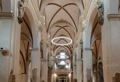 Wide view of a grand vaulted hall with historic pillars and modern circular lighting.