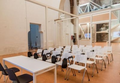 Bright seminar room with rows of white chairs and a presentation table.