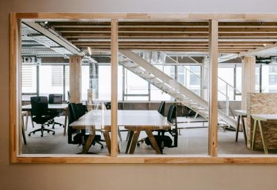Meeting room visible through a glass partition with a modern metal staircase in the background.