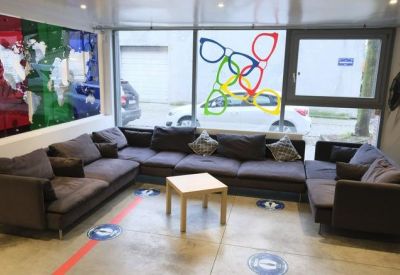 Lounge area with a large sectional sofa, world map art, and colorful window decals.